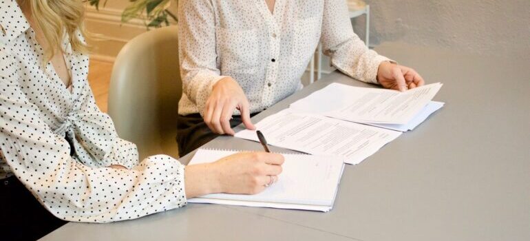 One women passing papers for signing to another woman