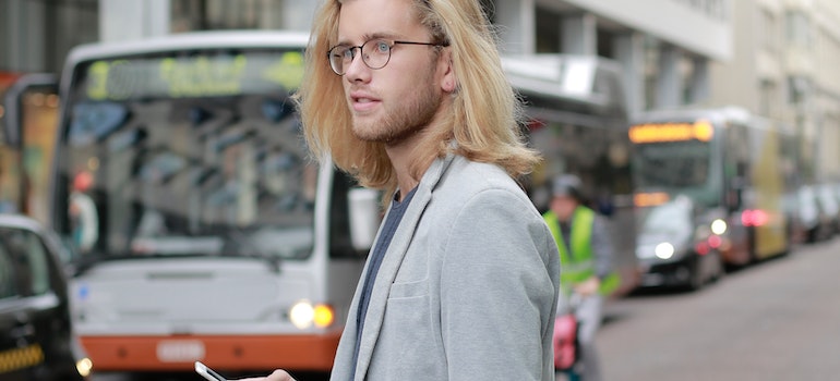 A man with long blonde hair waiting for a bus after moving from Maryland to New Jersey