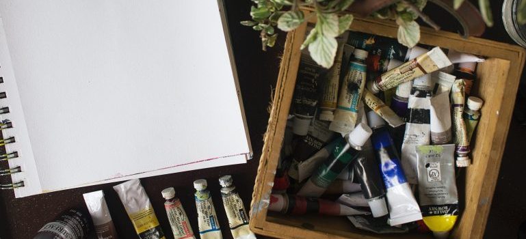 Art supplies in a wooden box next to paper