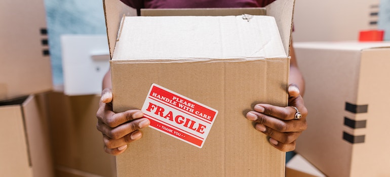 a mover from best cross country movers Bakersfield holding a box with fragile on it
