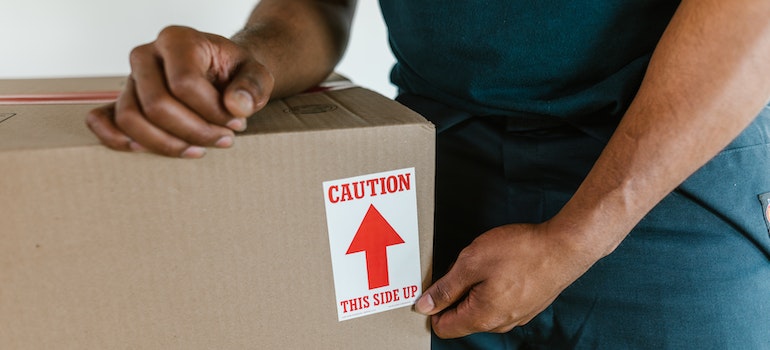 A man in green outfit putting a label on a cardboard box