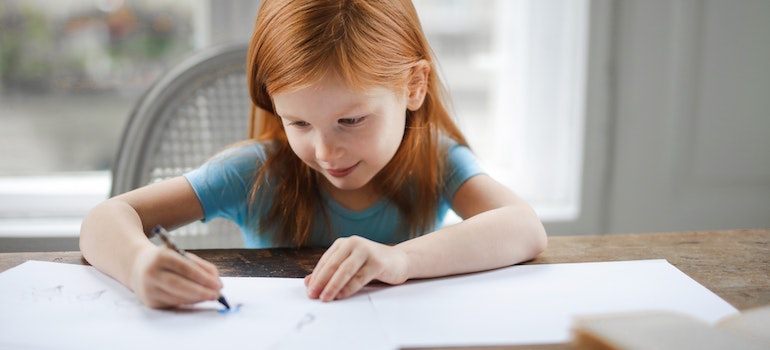 a little girl drawing on the paper