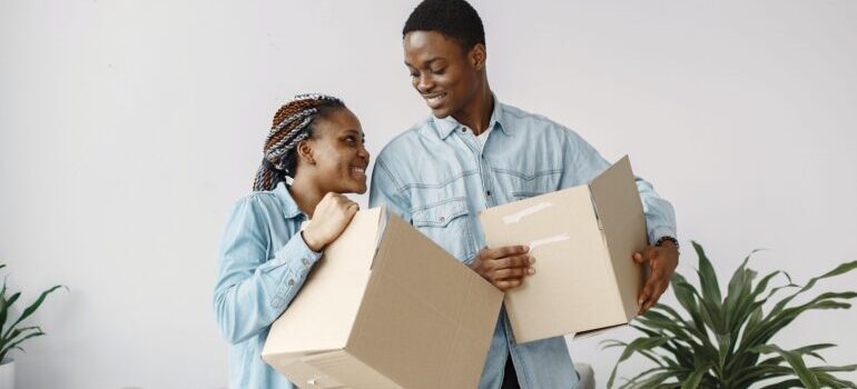 A couple holding cardboard boxes after moving into their new home with the help of best cross country movers Williston