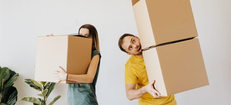 Man and woman holding cardboard boxes in a room