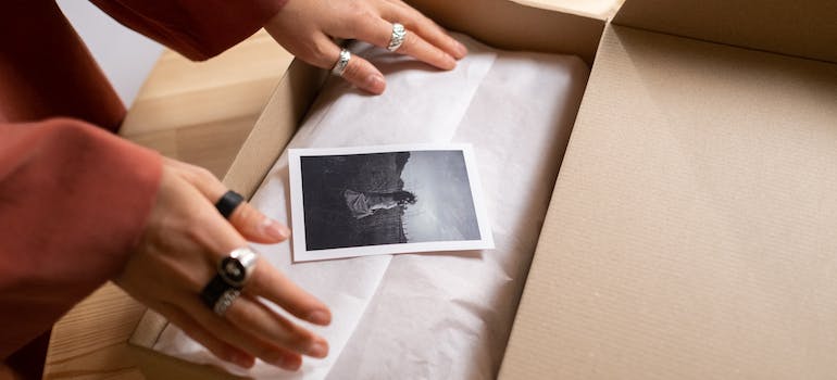 two hands packing a picture into a box