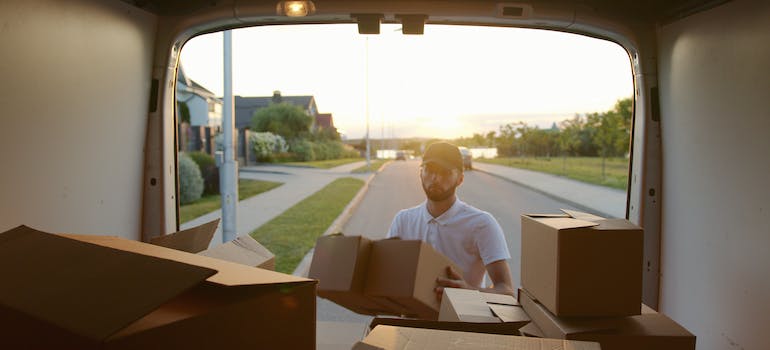 man putting a box into a van