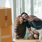 A couple taking a selfie while being surrounded by brown boxes