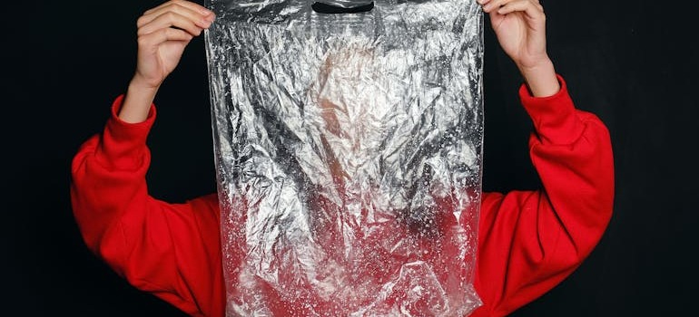 A person holding a plastic bag trying to pack liquids for moving