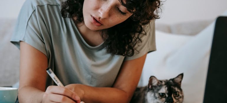A woman with her cat beside her exploring how to avoid moving scams