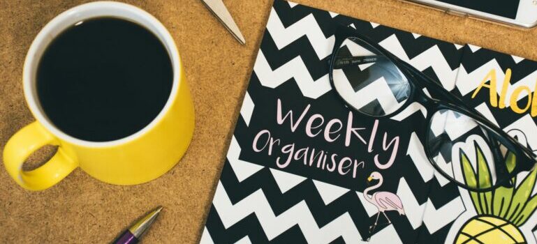 Weekly organiser and cup of cofee on the table